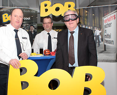 Marburgs Stadtverordnetenvorsteher, Heinrich Löwer, testet die Rauschbrille am BOB-Infostand mit den Polizeioberkommissaren Thomas Grimmelbein (links) und Stefan Becker 